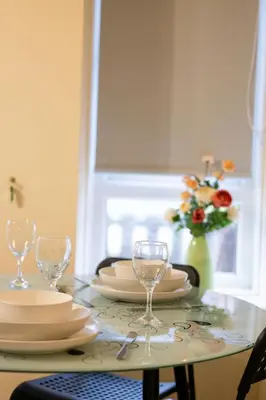 a table with plates and glasses and a vase of flowers at 53 Dorset street G3 7AG in Glasgow