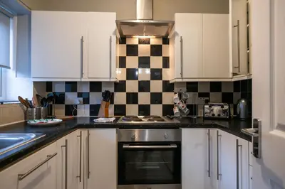 a kitchen with white cabinets and black and white tiles at 53 Dorset street G3 7AG in Glasgow