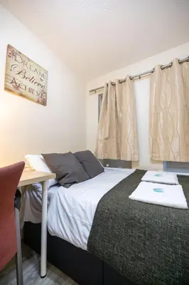 a bedroom with a bed and a desk and curtains at 53 Dorset street G3 7AG in Glasgow