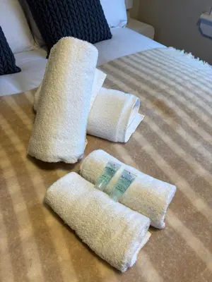 a bed with two towels and two pillows on it at Vacant Nests Ivy Cottage 3BR Wi-Fi in Kilsyth