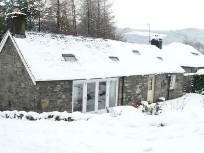 a stone house with snow on the roof at Burn Cottage - A Secluded Highland Retreat For Two in Fortingall