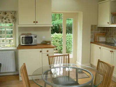 a kitchen with a glass table with chairs and a microwave at Burn Cottage - A Secluded Highland Retreat For Two in Fortingall