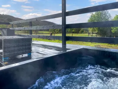 a hot tub on a patio with a fence at Riverview Lodge in Acharra