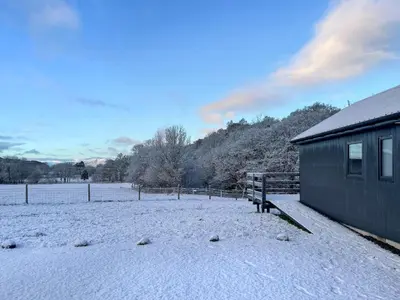 a snow covered field with a building and a fence at Riverview Lodge in Acharra
