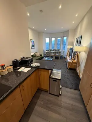 a kitchen with a counter and a living room at Spacious Tenement with free parking in Glasgow