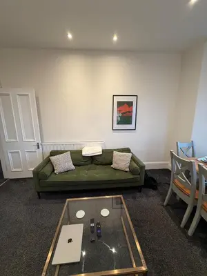 a living room with a green couch and a table at Spacious Tenement with free parking in Glasgow