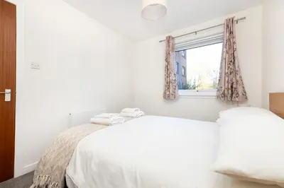 two beds in a white bedroom with a window at Edinburgh Morningside 2-Bedroom Apartment - Ground Floor in Edinburgh