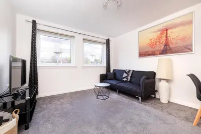 a living room with a couch and a tv at Edinburgh Morningside 2-Bedroom Apartment - Ground Floor in Edinburgh