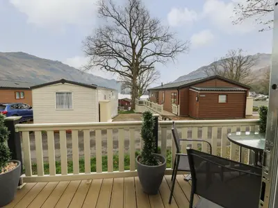 a deck with a white fence and a table and chairs at Loch Lomond Holiday home in Arrochar