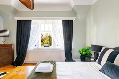 a living room with a bed and a window at Edwardian Manor hot tub & Pool in Glasgow, Gated in Giffnock