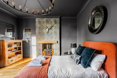 a bedroom with an orange bed and a clock on the wall at Edwardian Manor hot tub & Pool in Glasgow, Gated in Giffnock
