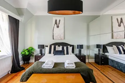 a bedroom with a large bed with a green blanket at Edwardian Manor hot tub & Pool in Glasgow, Gated in Giffnock