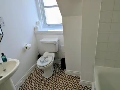 a white bathroom with a toilet and a sink at Littlebay Penthouse in Oban