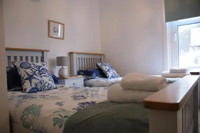 a bedroom with two beds with blue and white pillows at Inveree in Oban