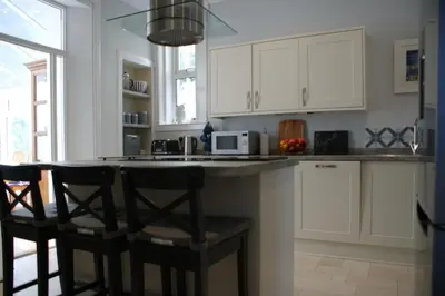 a kitchen with white cabinets and a counter with bar stools at Inveree in Oban