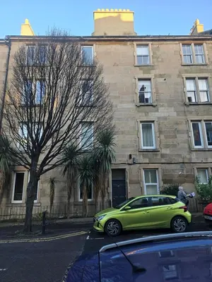 a green car parked in front of a building at Comfy Semi-Central Stay near Entertainment Park in Edinburgh