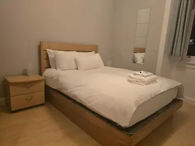 a bedroom with a bed with white sheets and a nightstand at Comfy Semi-Central Stay near Entertainment Park in Edinburgh