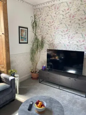 a living room with a large flat screen tv at The Bonnie Stay Garden Apartment in Largs