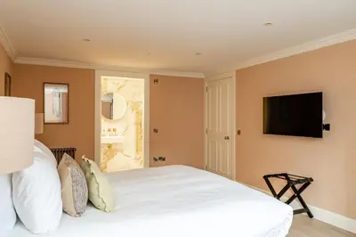 a bedroom with a white bed and a flat screen tv at Dragon Suites Luxury Apartments at Rutland Square in Edinburgh