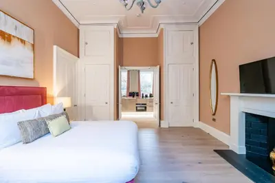 a bedroom with a white bed and a fireplace at Dragon Suites Luxury Apartments at Rutland Square in Edinburgh