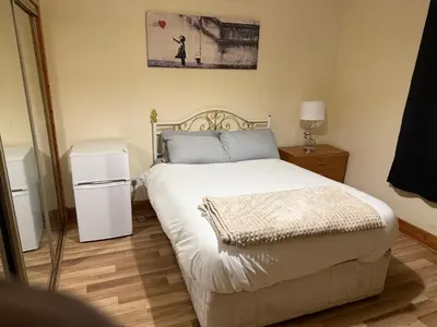 a bedroom with a large white bed and a small refrigerator at Happy home stay in Cowlairs