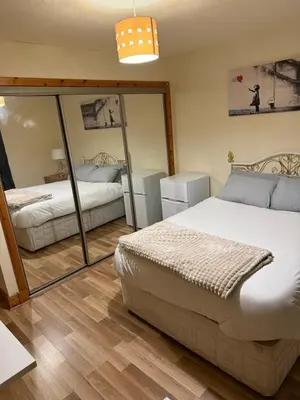 a bedroom with two beds and a large mirror at Happy home stay in Cowlairs