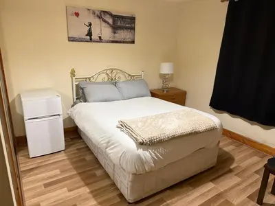 a bedroom with a bed and a table and a window at Happy home stay in Cowlairs