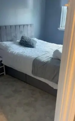a bed in a bedroom with a blue wall at 4 Bed Detached Home Perfect for Families & Groups in Glasgow