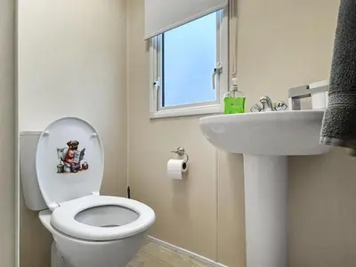 a bathroom with a toilet and a sink and a window at Ali B's Craig Tara in Ayr