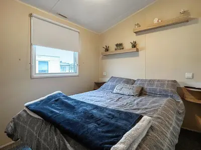 a bedroom with a bed with a blue blanket on it at Ali B's Craig Tara in Ayr