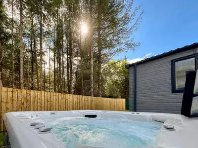 a hot tub in a yard next to a fence at Woodland View in Auchterarder