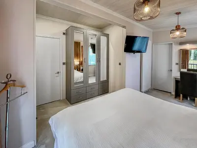 a bedroom with a white bed and a flat screen tv at Woodland View in Auchterarder