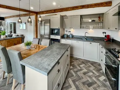 a kitchen with white cabinets and a wooden floor at Woodland View in Auchterarder