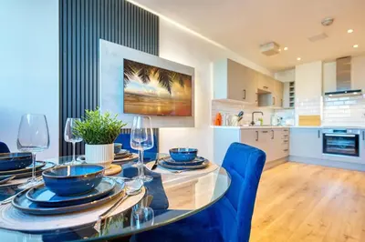 a kitchen and dining room with a table and blue chairs at Modern Luxe Apartment in Glasgow City Centre in Glasgow
