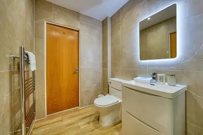 a bathroom with a toilet and a sink and a mirror at Modern Luxe Apartment in Glasgow City Centre in Glasgow