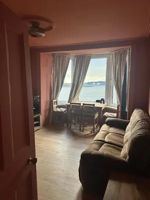 a living room with a couch and a view of the ocean at The Skipper's Rest in Millport