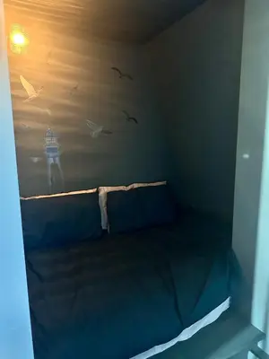 a small bed in a room with birds on the wall at The Skipper's Rest in Millport