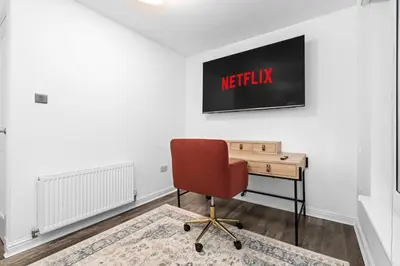 an office with a desk and a tv on the wall at Urban Elegance - Spacious 5-Bed Home in Glasgow in Glasgow