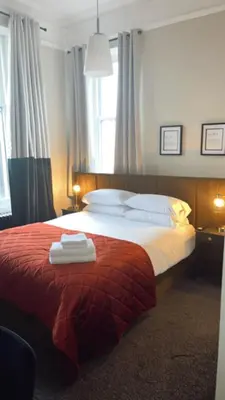 a bedroom with a bed with a red blanket and white pillows at The Graeme Hotel in Falkirk