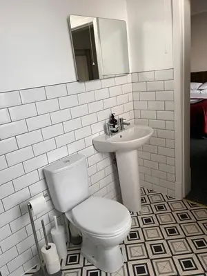 a white bathroom with a toilet and a sink at The Graeme Hotel in Falkirk