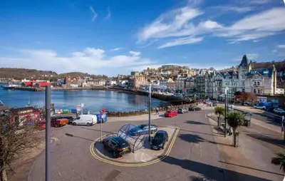 a city with cars parked in a parking lot near the water at Bay View Apartment in Oban