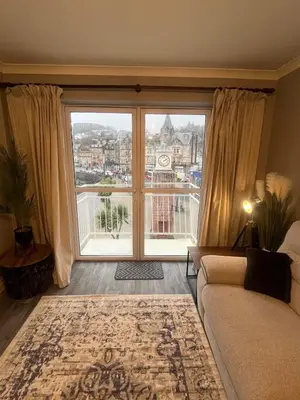 a living room with a couch and a large window at Bay View Apartment in Oban