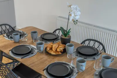 a wooden table with black plates and food on it at Modern 2-Bed Flat with Balcony and Free Parking - Ideal for Contractors in Moffat