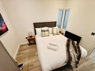 a bedroom with a large bed with white sheets and pillows at Bright 2-Bed Apartment in Bury Town Centre in Moffat