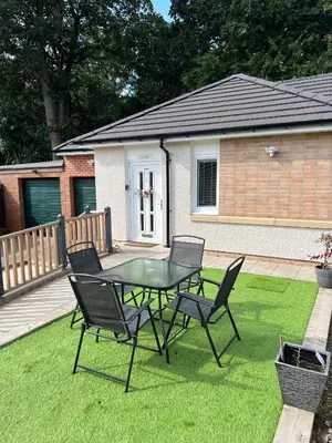 a patio with a table and chairs on the grass at Canal View Cottage in Winchburgh