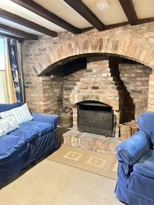a living room with a stone fireplace with blue couches at Garden flat at Broomfield in Moffat