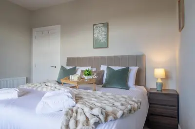 a bedroom with a large white bed with a blanket at Pinkerton House - 3 bed Rutherglen in Glasgow