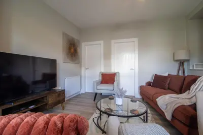 a living room with a couch and a flat screen tv at Pinkerton House - 3 bed Rutherglen in Glasgow