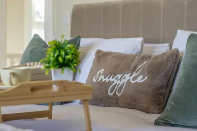 a bed with green pillows and a pillow with the word suicideigunigunigun at Pinkerton House - 3 bed Rutherglen in Glasgow