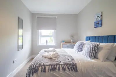 a bedroom with a bed with a blue headboard at Pinkerton House - 3 bed Rutherglen in Glasgow